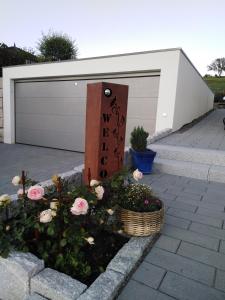 a sign with flowers in a basket in front of a garage at Eva's Ferienwohnung in Bonndorf im Schwarzwald