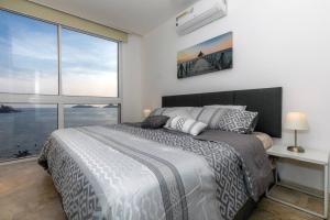 una camera da letto con un letto grande e una grande finestra di Luxury apartment in front of Acapulco Beach ad Acapulco Altre 26 foto