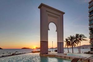 un monumento sulla spiaggia con il tramonto sullo sfondo di Luxury apartment in front of Acapulco Beach ad Acapulco