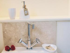 ein Waschbecken mit einem Wasserhahn und roten Rosen in der Unterkunft Ottery St Mary Cottages in Ottery Saint Mary + 19 Fotos