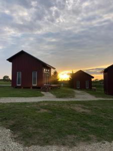 a couple of barns with the sunset in the background at Ambro Krasts in Maskava