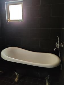 a bath tub in a black bathroom with a window at Omenapolun Onni in Taipalsaari