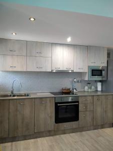 cocina con armarios de madera, fregadero y microondas en Corfu Sunset family apartment, en Liapades