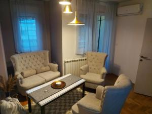 uma sala de estar com um sofá, uma mesa e cadeiras em River Lux em Sremska Mitrovica
