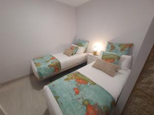 two twin beds in a room with a map of the world at Casa Jalecha in Muxia