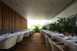 a restaurant with white tables and chairs and plants at Scheiblhofer The Resort in Andau