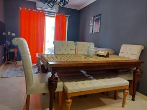 a dining room with a wooden table and white chairs at Trendy House in Badr