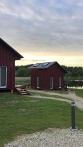 a red barn with a black roof next to a building at Ambro Krasts in Maskava