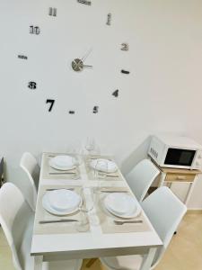 a white table with white plates and a microwave at APARTAMENTO SOL in Viveiro +6 photos