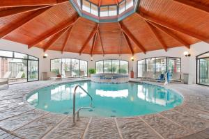 une grande piscine intérieure avec un plafond en bois et des fenêtres dans l'établissement Best Western Plus Swiss Chalet Hotel & Suites, à Pecos