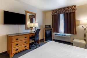 a hotel room with a bed and a desk with a television at Best Western Brighton Inn in Brighton