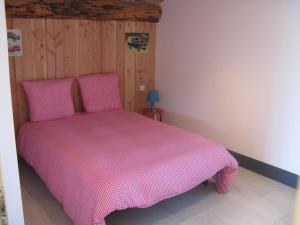 a bedroom with a pink bed with a wooden wall at Chambre d'hôtes Chez Karine et Roland in Le Fied