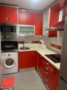 a red kitchen with a sink and a washing machine at Apartamento con garaje en Paseo Marítimo de Barbate in Barbate +3 photos