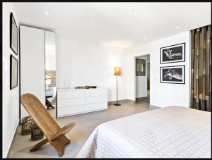 a white bedroom with a white bed and a chair at Puerto Banus luxury apartment located in harbor in Marbella