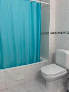 een badkamer met een toilet en een blauw douchegordijn bij Apartamento T1 Monte Gordo in Monte Gordo