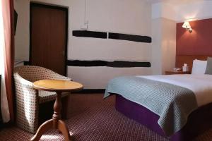 a hotel room with a bed and a small table at The Tudor Hotel in Harrow