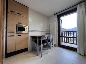 eine Küche mit einem Tisch, einer Mikrowelle und einem Fenster in der Unterkunft Escarra - Reformado, acogedor y luminoso, con garaje cubierto y ascensor in Escarrilla
