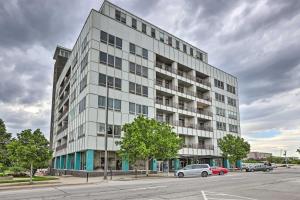 a tall white building with cars parked in a parking lot at 7th-Floor Omaha Condo with Balcony and Park Views in Omaha