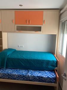 a bedroom with a bed with blue sheets and orange cabinets at Apartamento con garaje en Paseo Marítimo de Barbate in Barbate