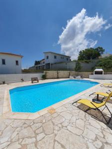a swimming pool with two chairs and a table at VILLA SERAPHO in Paphos