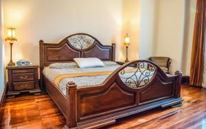 Cama grande de madera en habitación con 2 lámparas en Amon Mansión, en San José