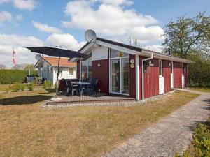 una pequeña casa roja con una mesa y una sombrilla en Two-Bedroom Holiday home in Grömitz 11, en Grömitz