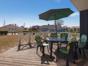 a table and chairs with a green umbrella on a deck at 6 person holiday home in GROEMITZ in Grömitz