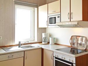 a kitchen with white cabinets and a sink and a microwave at 6 person holiday home in Otterndorf in Otterndorf