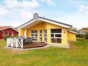 una casa amarilla con terraza en un patio en 6 person holiday home in GROEMITZ, en Grömitz