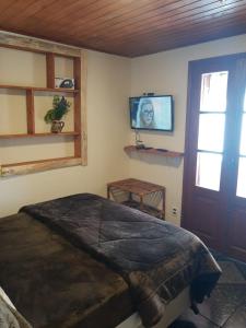 a bedroom with a bed and a tv on the wall at Recanto das Glicínias in Monte Verde