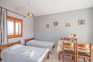 een kamer met 2 bedden en een tafel en stoelen bij Pine tree Apartment & sunset in Ágios Nikólaos