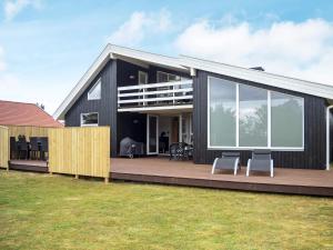 Nørre Vorupørにある10 person holiday home in Thistedの黒い家 白い椅子2脚付きのデッキ