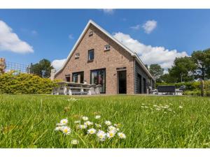 a brick house in a field of grass with flowers at Family Home in Zeeland near Oranjezon Beach in Vrouwenpolder +32 photos