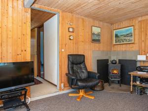 een woonkamer met een leren stoel en een televisie bij 4 person holiday home in Alling bro in Allingåbro