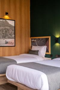 a bedroom with two beds and a green wall at LOKAL Rooms x Hunza (5 Peaks) in Baltit