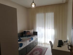 a bedroom with a bed and a desk and a window at Appartement Résidence fermée in Casablanca