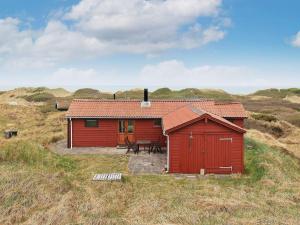una cabina rossa in mezzo a un campo di Three-Bedroom Holiday home in Løkken 31 a Grønhøj