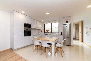 a kitchen with white cabinets and a wooden table and chairs at Ria Sal apartments in Aveiro