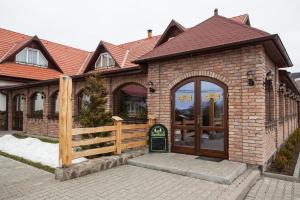 een stenen huis met een hek en een hek bij Pensiunea Laci Csarda Ernei in Ernei