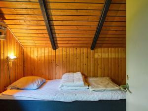 a bed in a room with a wooden wall at Three-Bedroom Holiday home in Rødby 28 in Kramnitse