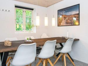 ØbyにあるFour-Bedroom Holiday home in Ulfborg 5のダイニングルーム(木製テーブル、白い椅子付)