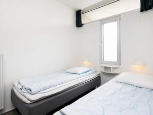 two beds in a room with a window at 4 person apartment in holiday park Blokhus in Blokhus +13 photos