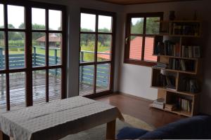 a living room with windows and a table and book shelf at Pakalnės vingis in Rusnė