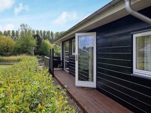 Casa negra con terraza de madera y ventana en 6 person holiday home in Tranekær-By Traum, en Tranekær