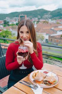 una mujer sentada en una mesa con una copa de vino en Hotel Casa del Barranco, en Cuenca