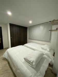 a bedroom with a large bed with white sheets and pillows at Acogedor alojamiento con piscina cerca al mar! in Gaira