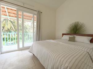 a white bedroom with a bed and a large window at Beseco Bed and Breakfast in Benaulim