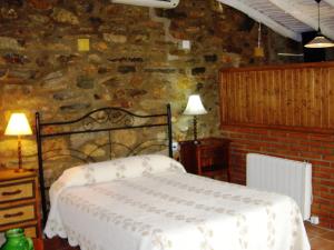 1 dormitorio con cama y pared de piedra en Studio on rural authentic finca with shared pool, en La Borrega