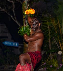 un hombre con una máscara en la cara sosteniendo una flor en Likuri Island Resort Fiji, en Natadola