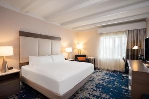 アルバニーにあるCrowne Plaza Albany - The Desmond Hotelの白い大型ベッド1台、デスクが備わる客室です。